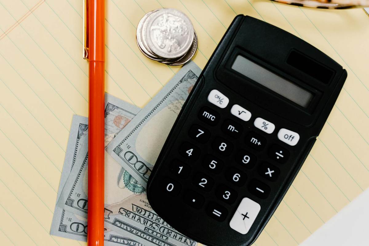Calculator and coins showing buy me a coffee fee calculation at each revenue tier