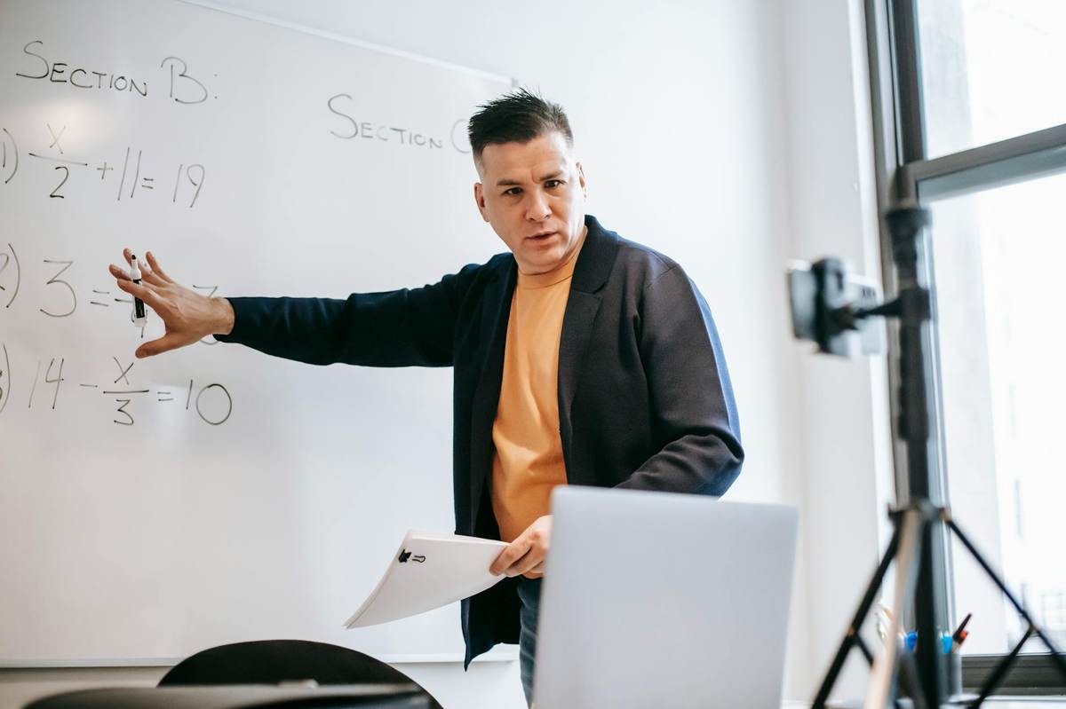An educator setting up an online course on a laptop in a modern teaching environment