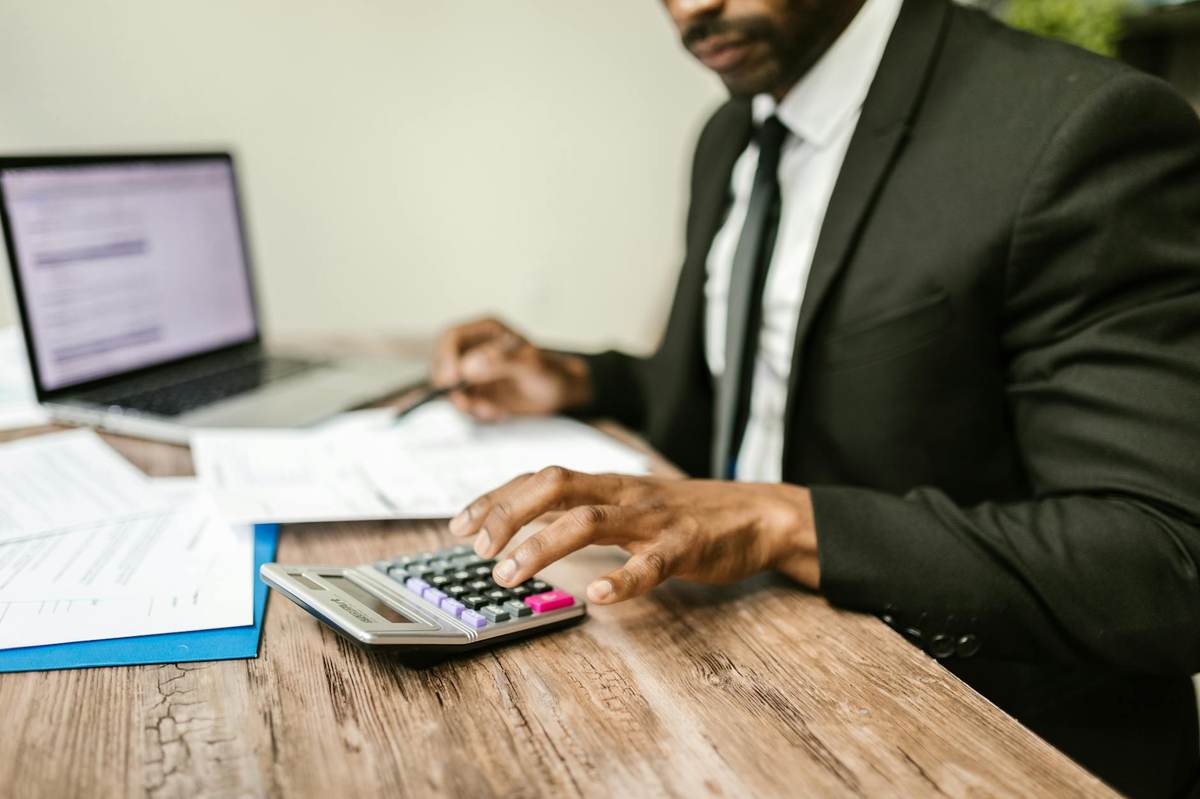 Entrepreneur calculating creator revenue and subscription fees on a laptop