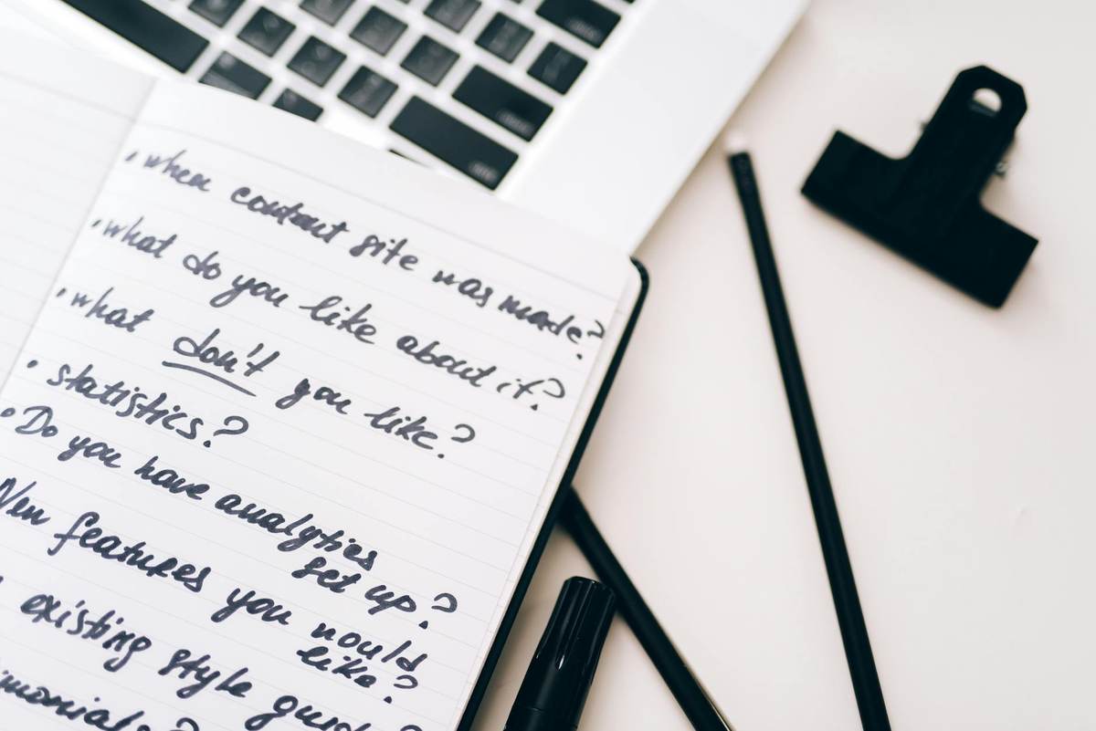 Content creator planning niche and pricing strategy at a laptop with notebook